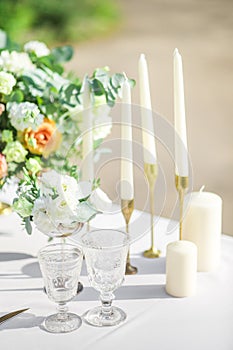 Decorated wedding table with beautiful flower composition, candles and glasses, outdoor, fine art.