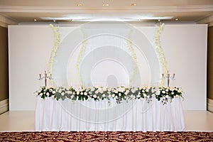 Decorated wedding table in the restaurant, flowers and a lavish chandelier.