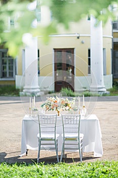 Decorated wedding table for two with beautiful flower composition, glasses for wine, candles and plates, outdoor, fine
