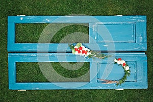 Decorated wreath of flowers, leaves and dry grass on a wooden blue door background. Copy, empty space for text
