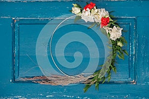 Decorated wreath of flowers, leaves and dry grass on a wooden blue door background. Copy, empty space for text