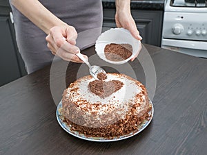 Decorating a cake for Valentine`s day. Handmade pie with cream cheese frosting and a chocolate heart.