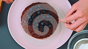 Decorating a chocolate cake with blueberries