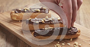 Decorating eclairs with hazelnuts on wood board