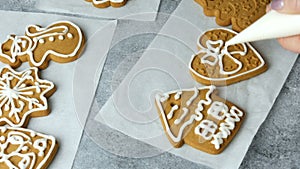 Decorating holiday gingerbread cookie. Hand take pastry bag with sweet white icing. Making handmade festive new year