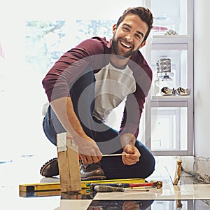 Decorating one tile at a time. Portrait of a smiling man laying floor tiles.