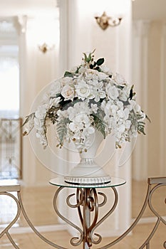 Decoration of artificial flowers in a vase in a ceremonial hall at a wedding ceremony, a close-up detail, a stand or a