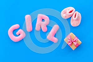 Decoration for baby`s birthday. Word girl near booties and present box on blue background top view