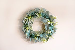 Decoration for Easter in the form of a wreath of eucaliptus branches on a beige wall