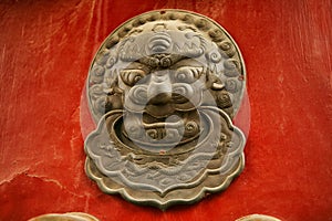 The decoration element of a red wooden door in the form of a lion`s head in the Forbidden City, Beijing, China