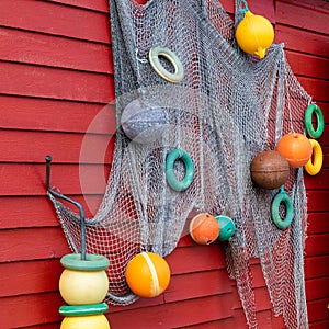 decoration of fishing net and colorful buoys on a red painted wooden house on the loftoen in norway