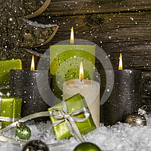 Decoration: four green and brown burning advent candles for christmas with presents.