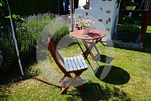 Wooden table and chairs stand on the lawn in the garden against the background of purple lavender flowers. Berlin, Germany