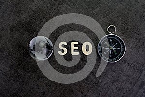 Decoration globe, alphabet SEO and compass on dark cement chalkboard background using as SEO Search engine optimization concept