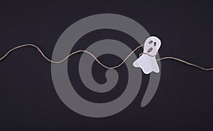 Decoration for Halloween party - laughing flying scary specter or spirit, handing on a rope on a black background. Flat lay
