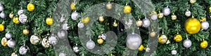 Decoration hanging from a christmas tree. Gold and silver balls hanging on the green Christmas tree closeup.