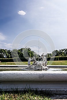 Decoration statue of a medieval fountain in the garden on the background of bright sky. Water spraying out of stature on fountain