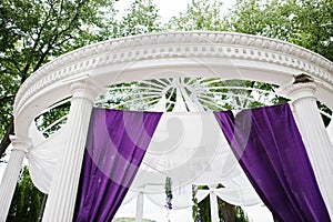 Decoration of wedding arch with violet and white cloth outdoor.