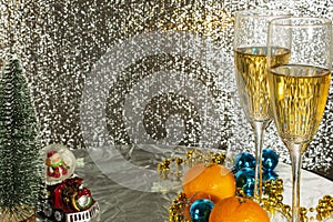 Decoration for winter holidays. On a silver table are two glasses of champagne, tangerines and festive decor.