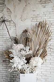Decorations from dry beautiful flowers in a white vase on a beige fabric background. Home room decoration