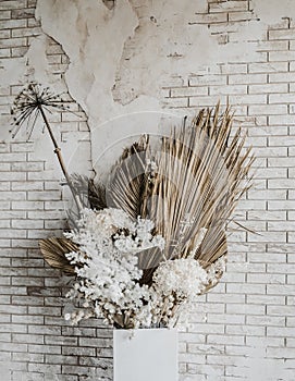 Decorations from dry beautiful flowers in a white vase on a beige fabric background. Home room decoration