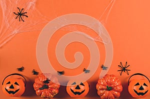 Decorations for Halloween on an orange background, copy space. Pumpkins and spiders in a web on an orange background, top view