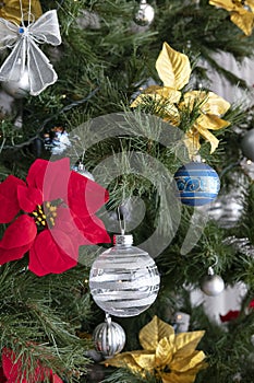 Decorations hanging from a Christmas tree, golden and red velvet poinsettias, fancy ribbons, vintage baubles and fancy lights