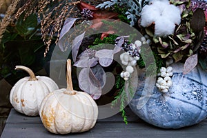 Decorations of multi-colored pumpkins and dried flowers in front of entrance to flower shop on Thanksgiving. Ð¡oncept greeting