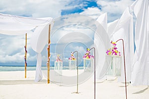 Decorations of wedding arch with white flowers and candles at beach. Luxury destination wedding background