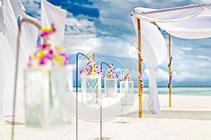 Decorations of wedding arch with white flowers and candles at beach. Luxury destination wedding background