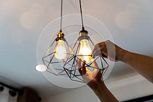 Decorative antique edison style filament light bulbs hanging. An electrician is installing spotlights on the ceiling