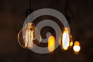 Decorative antique edison style light bulbs on the dark wall background. Loft interior details