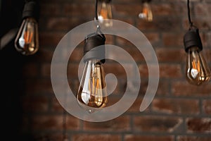 Decorative antique edison style light tungsten bulbs against brick wall