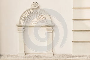 Decorative arch and semi vault above niche with classic pillars. Architectural stucco detail of old European buildingin