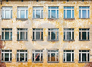 Decorative background - wall, windows. The photo shows the orange wall of the old school and many windows, in one of which a toy