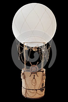 Decorative balloon on a black background with a basket, ropes and a helm