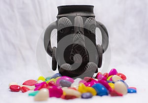 A decorative black pen stand surrounded by colored stones kept in a white copy space background.