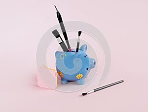 Decorative blue pig, makeup brushes on a pink background