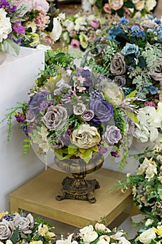 Decorative bouquet of artificial roses, blue white purple fabric flowers in a metal vase, vertical