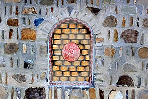 Decorative bricked window in a stone wall