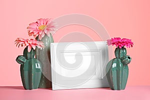 Decorative cacti, flowers and photo frame on table against color background. International Women`s Day