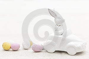 Decorative ceramic hare in a car and Easter eggs, close-up.