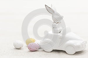 Decorative ceramic hare in a car and Easter eggs, close-up.
