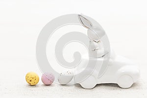 Decorative ceramic hare in a car and Easter eggs, close-up.