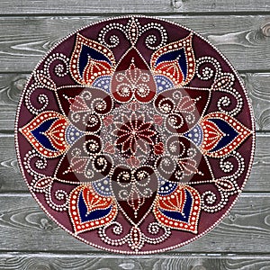 Decorative ceramic plate, hand painted dot pattern with acrylic paints on a gray wooden background. A square photo. Closeup