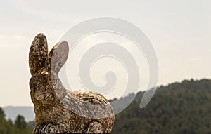 decorative ceramic rabbit with an out-of-focus mountain image in the background