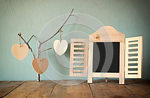 Decorative chalkboard frame and wooden hanging hearts over wooden table