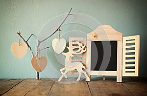 Decorative chalkboard frame and wooden hanging hearts over wooden table. ready for text or mockup. retro filtered image