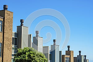 Decorative chimneys in row in neighborhood with wooden slats or panels with metal tops and gradient blue and white sky