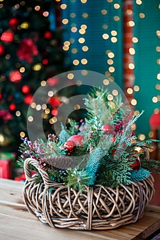 The decorative Christmas basket is located on a table on the background of a Christmas tree.